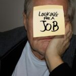 Uomo e donna discutono di pensione anticipata in un ufficio, con documenti e calcolatrice.